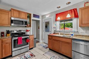 a kitchen with wooden cabinets and a stove top oven at Coca Cola Cottage - Stay & Play Near Purina Farms - Dog Friendly in Pacific