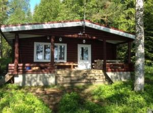 eine Blockhütte im Wald mit einer Veranda in der Unterkunft Seitsemisen kansallispuisto Aurejärvi Parkano in Parkano