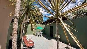 a patio with two palm trees and a table and chairs at Boa Vista Suítes in Água Boa