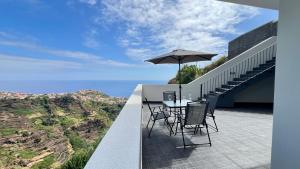 a table and chairs on a balcony with an umbrella at The Barreto's Clive in Ponta do Sol