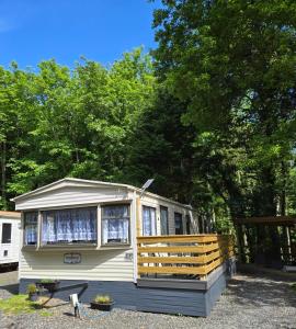 a small yellow caravan with a fence and trees at Unique Caravan with Outdoor Space in Ballantrae
