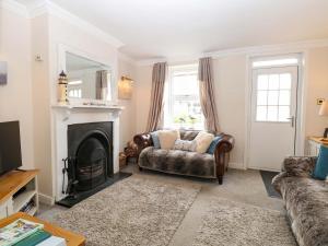 a living room with a couch and a fireplace at Fern Cottage in Heacham