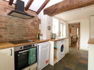 a kitchen with a stove and a washer and dryer at Fern Cottage in Heacham