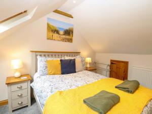 a bedroom with a yellow bed and two lamps at Fern Cottage in Heacham