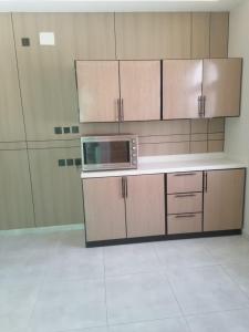 a kitchen with wooden cabinets and a microwave at شقة 3 احد رفيدة حي الخليج in Ahad Rafidah