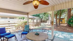 a patio with a table and chairs and a ceiling fan at BEACHY SISTERS A Duplex in Jekyll Island