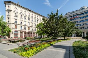 a park with benches and flowers in front of a building at Csarnok Apartment in Budapest