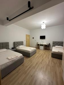 a room with two beds and a desk with a tv at Hotel Aulona in Fier +16 photos