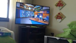 a flat screen tv sitting on a stand in a room at CASA COM 3 QUARTOS, SENDO 1 QUARTO Suite in Pinhal