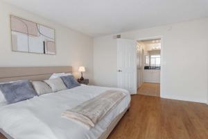 een slaapkamer met een groot wit bed en een houten vloer bij Marina Edge Bright 1BR 1BA Condo by the Beach in Los Angeles