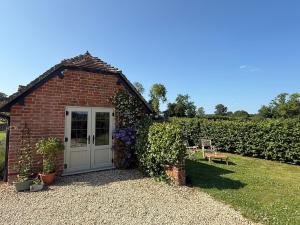 a small brick shed with a white door and flowers at Meadow Hayes Studio in Shaftesbury