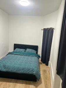 a bedroom with a bed with blue sheets and blue curtains at Appartement de caractère Val 1 in Beaumont