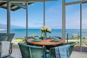 a dining room with a table and chairs and the ocean at Surfers Paradise in Santa Barbara