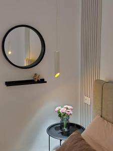 a table with a mirror and a vase of flowers on it at Feel like home 2 in Shkodër