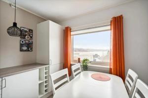 ein Esszimmer mit einem weißen Tisch und Stühlen und einem Fenster in der Unterkunft Narvik Panorama Apartment in Narvik