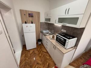a small kitchen with a microwave and a refrigerator at Apartman Dunja 2 in Šid