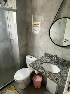 ein Badezimmer mit Toilette, Waschbecken und Spiegel in der Unterkunft Apartamento Guarujá Lazer completo Villa Di Fiori 600mts da praia in Guarujá + 18 Fotos