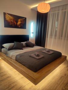 a bedroom with a large bed with towels on it at Lux Apartman JELAČIK in Subotica