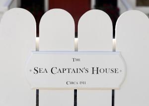 a sign for the sea captains house on a white fence at The Sea Captains House & Loft by Paradise Retreats in Santa Barbara