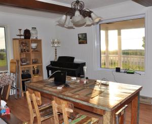a living room with a wooden table and a piano at Couchers de soleil à Sainte-Flavie in Sainte-Flavie