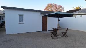 a white building with two chairs and an umbrella at Serenity in Windhoek