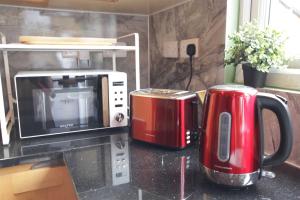 Dos electrodomésticos rojos sobre un mostrador junto a un microondas. en Guesthouse - Georgias Gate, en Errill