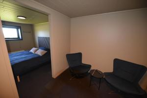 a room with two chairs and a bed and a window at Senja Beach Lodge in Senja
