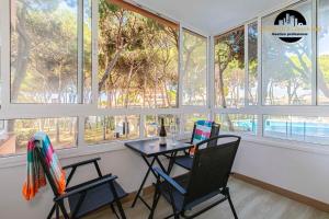 Dos sillas y una mesa en una habitación con ventanas. en Apartamento Calypso, en Sitio de Calahonda