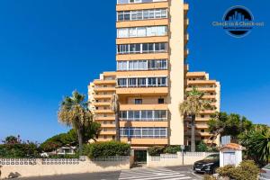 Un edificio alto con palmeras delante. en Apartamento Calypso, en Sitio de Calahonda