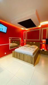 a bedroom with a large bed with red walls at Oásis Motel in Pôrto Ferreira