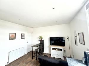 a living room with a couch and a tv at Cozy hotel-style city apartment in Amley