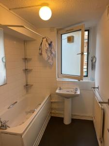 uma casa de banho com uma banheira, um lavatório e uma janela em GX Property em Londres