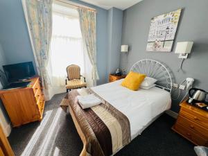 a bedroom with a bed and a chair and a window at The George Hotel in Montrose