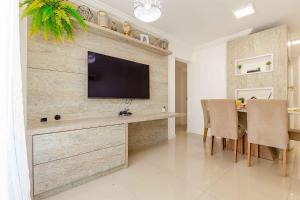 a living room with a television on a wall at Apto Confortável e Econômico na Praia de Bombas in Bombas