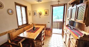 a kitchen with a wooden table and some windows at Ciasa Nuvola Apartment in Cibiana