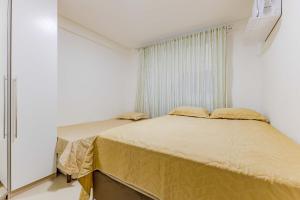a small bedroom with two beds and a window at Apto Confortável e Econômico na Praia de Bombas in Bombas
