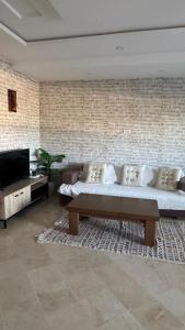 Una sala de estar con un sofá y una pared de ladrillos. en Apparemment luxe, en Mahdia