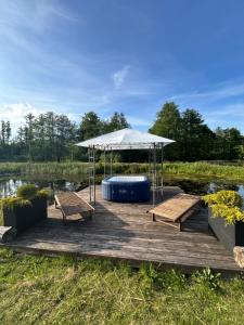 a wooden dock with a tent and benches on a lake at Monasteria in Stare Monasterzysko