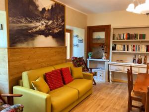 a living room with a yellow couch with red pillows at Cà d'Margherita and Heidi in Valdieri