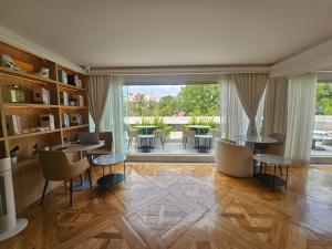 een woonkamer met tafels en stoelen en een groot raam bij Residence L Heritage Tennyson in Mexico-Stad