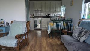 An Teach Beag Glencolmcille, little home from home في غلينكولومبكيل: غرفة معيشة مع أريكة ومطبخ