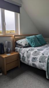 An Teach Beag Glencolmcille, little home from home في غلينكولومبكيل: غرفة نوم بها سرير وطاولة ومصباح