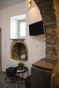 a living room with a stone fireplace and a tv at Omnia Apartments Amorgos Studio in Amorgos