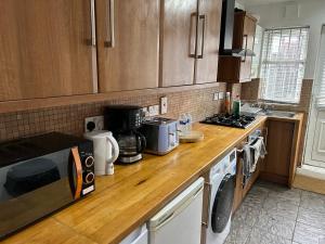 a kitchen with wooden cabinets and a counter top at A Cosy Ground Floor Flat in London +13 photos