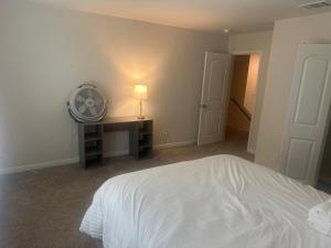 a bedroom with a white bed and a desk with a fan at Cozy, Comfy and Relaxing! 
