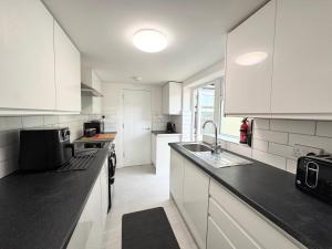 a kitchen with white cabinets and black counter tops at Entire 5 Bed New Home - Southampton Centre - 4BDRM in Southampton