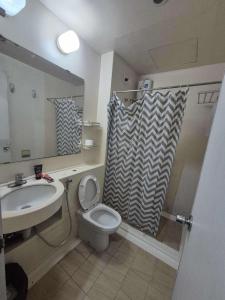 a bathroom with a sink and a toilet and a shower curtain at bayviewmansion malate in Manila