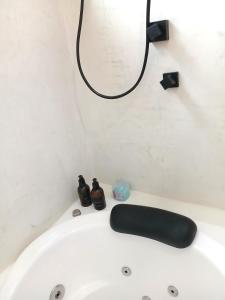 a white bath tub with a black light on the wall at Suíte Casal com Hidro no Centro - Infinito Particular in Guararema