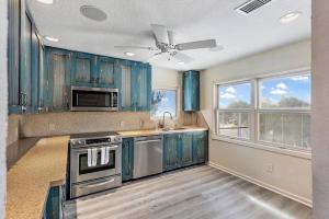 a kitchen with blue cabinets and a ceiling fan at Treasure Island Waterfront home - 100ft to beach! in St Pete Beach