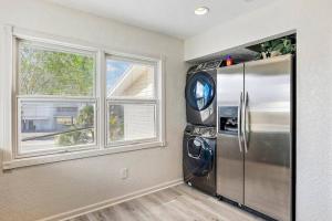 a kitchen with a stainless steel refrigerator and two windows at Treasure Island Waterfront home - 100ft to beach! in St Pete Beach